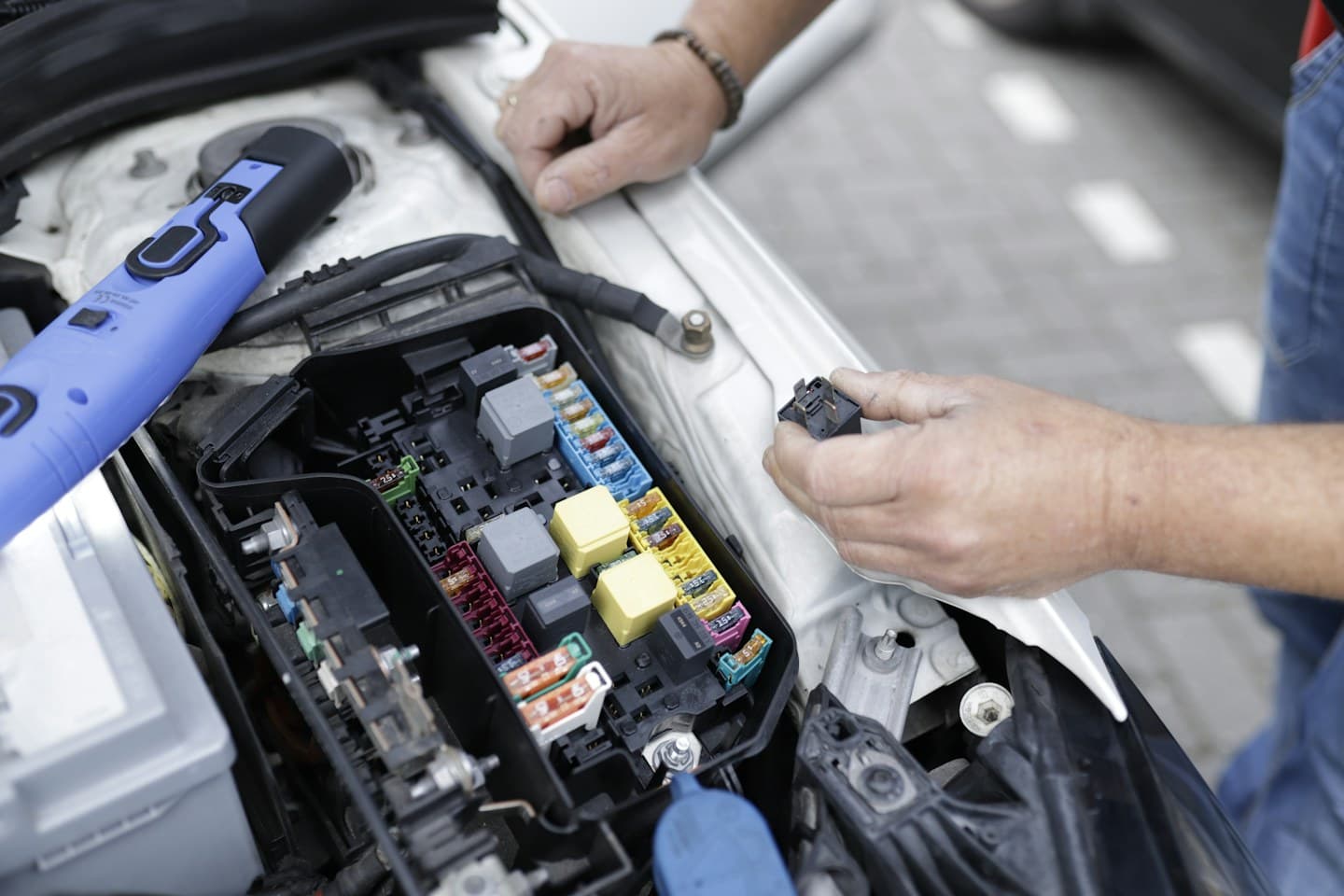 Technician inspecting a car’s engine and electronics